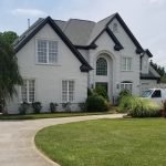 After picture of a beautifully maintained brick house with a lush green lawn by house painters in Charlotte, NC.