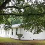 After picture of a house exterior by house painters in Charlotte, NC, showcasing a newly painted white brick exterior surrounded by trees.