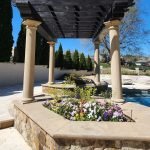 Beautifully painted pergola and columns by a painting company in Charlotte, NC, enhancing the outdoor space with vibrant flowers and a pristine pool.