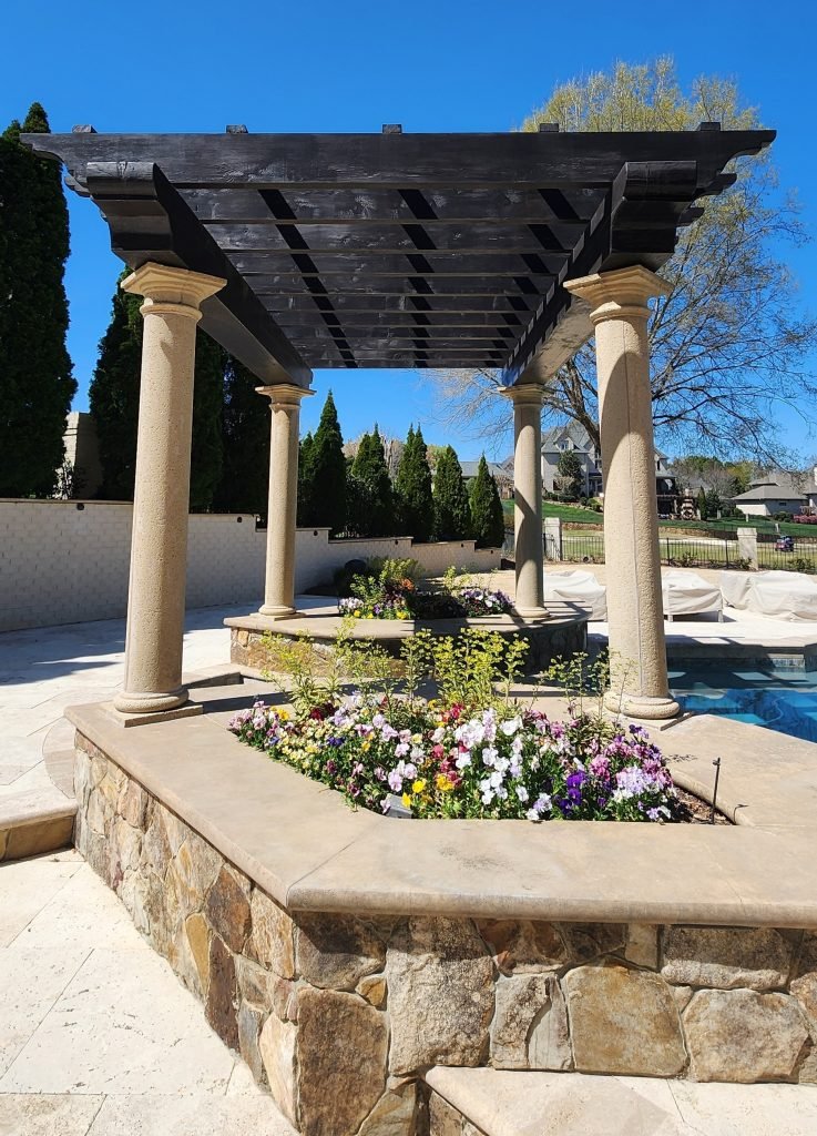 Beautifully painted pergola and columns by a painting company in Charlotte, NC, enhancing the outdoor space with vibrant flowers and a pristine pool.