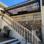 Elegantly painted staircase and pergola by a painting company in Charlotte, NC, featuring a stone wall and outdoor decorations.