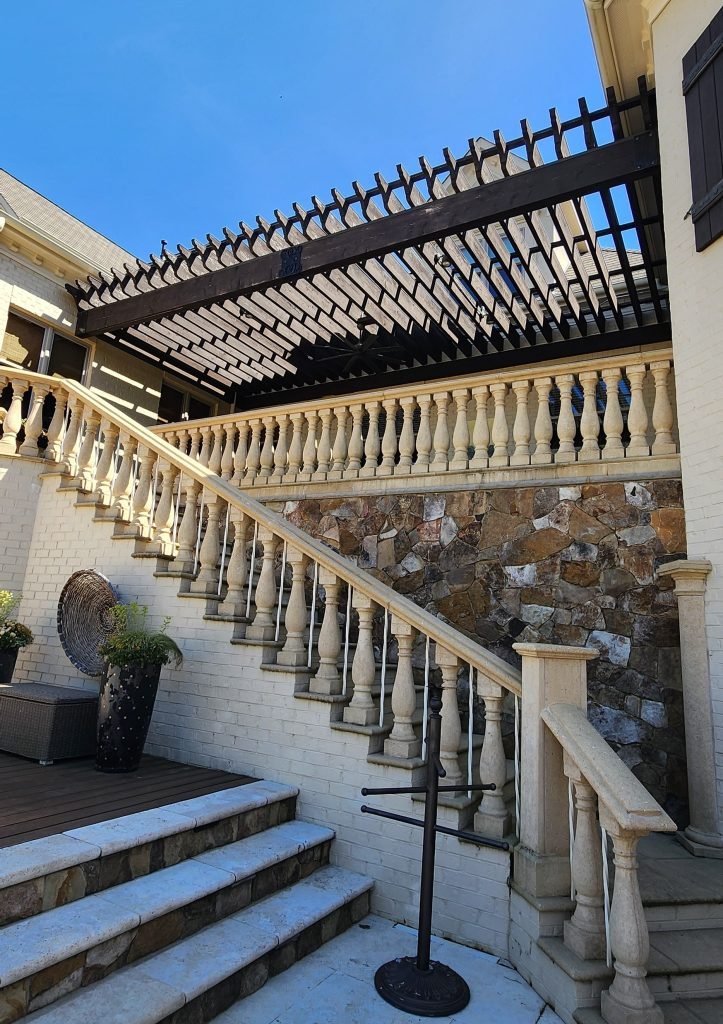 Elegantly painted staircase and pergola by a painting company in Charlotte, NC, featuring a stone wall and outdoor decorations.