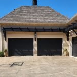 Freshly painted black garage doors by house painters in Charlotte, NC, under a clear blue sky.