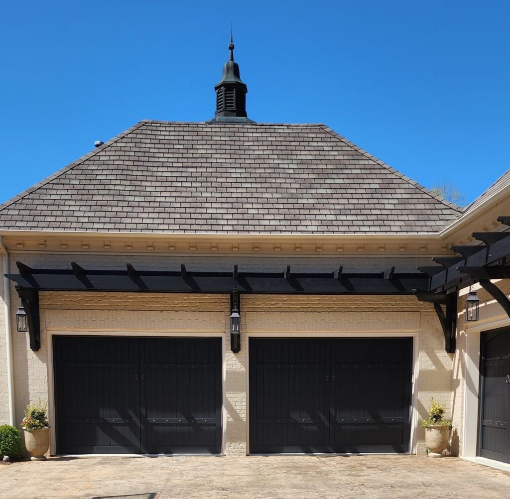 Freshly painted black garage doors by house painters in Charlotte, NC, under a clear blue sky.