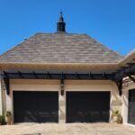 Freshly painted black garage doors by house painters in Charlotte, NC, under a clear blue sky.