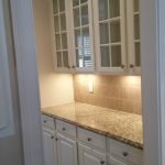 Beautifully painted white cabinets with glass doors and granite countertop by interior painting services in Charlotte, NC.