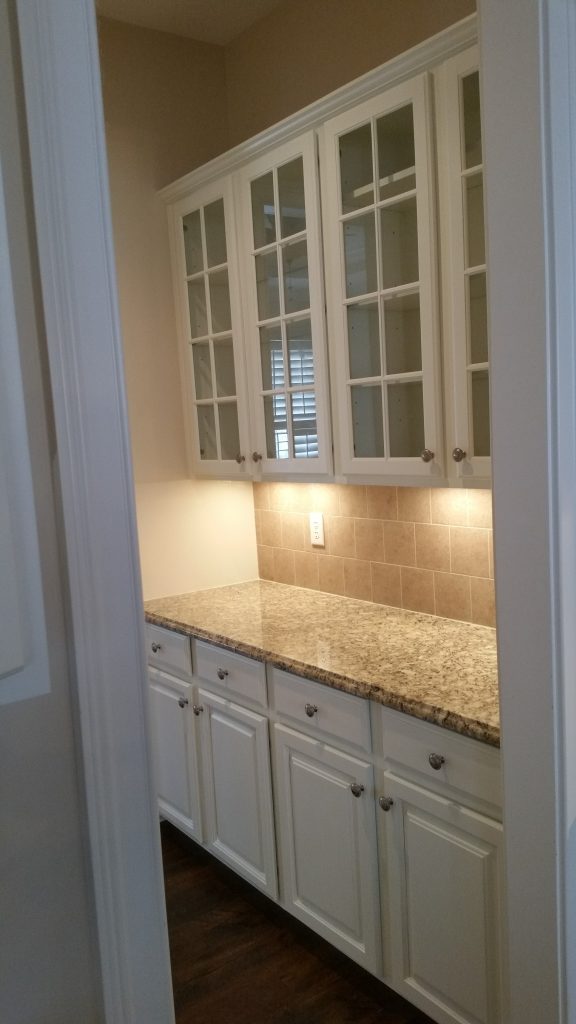 Beautifully painted white cabinets with glass doors and granite countertop by interior painting services in Charlotte, NC.