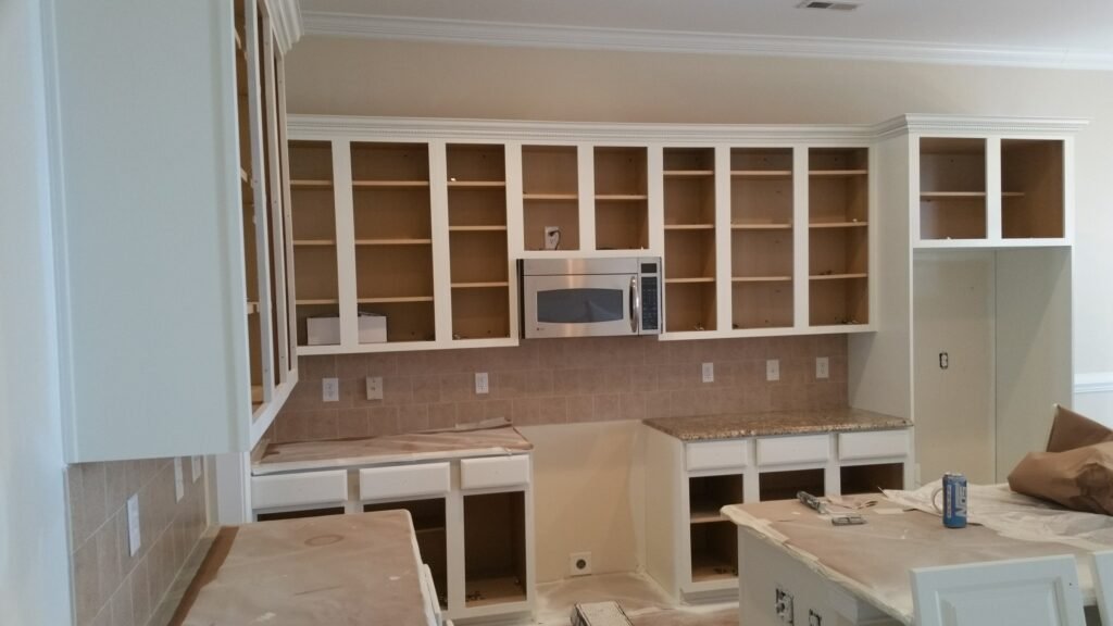 Freshly painted kitchen cabinets undergoing a professional makeover in Charlotte, NC, highlighting the transformation and neat arrangement.
